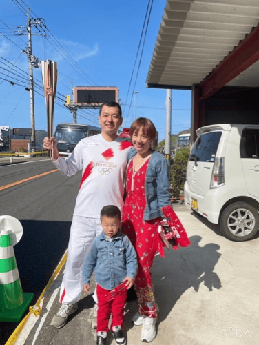 Tatsuo carrying the Olympic torch along the street named after de Morais